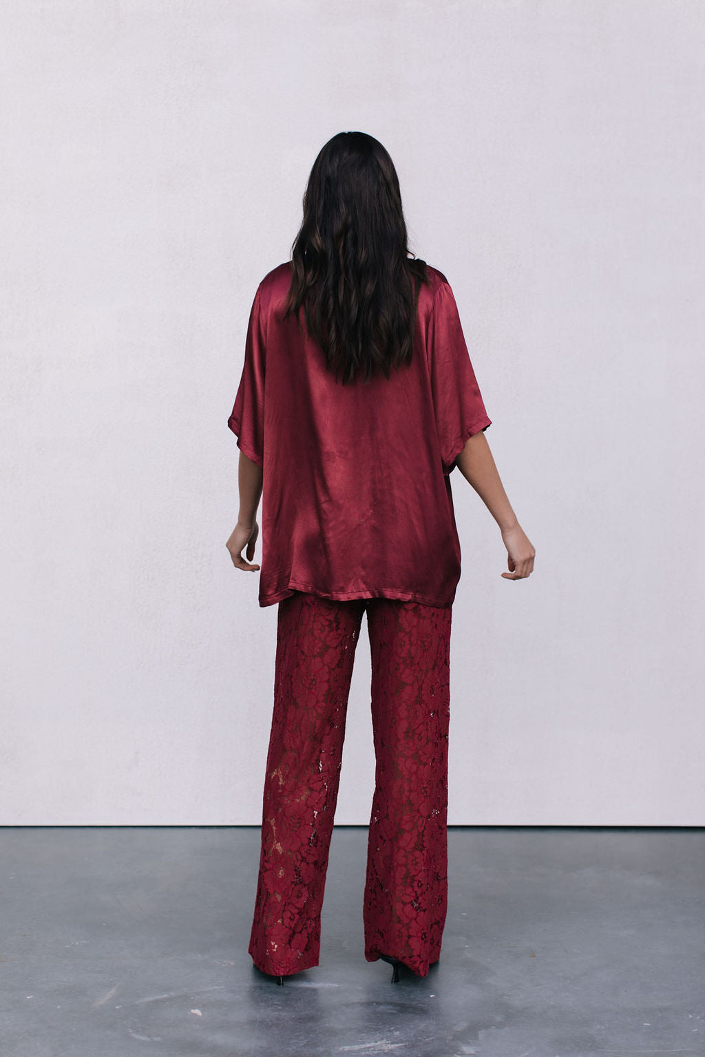Person wearing a red burgundy satin outfit with a plain white background