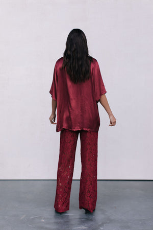 Person wearing a red burgundy satin outfit with a plain white background