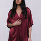 Woman wearing a burgundy satin shirt with lace pants on a white background
