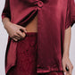 Burgundy satin top and lace pants on a plain background