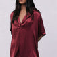 Woman wearing a burgundy satin top with lace pants on a white background