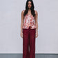 Woman wearing a floral top and red lace pants against a plain background