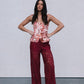 Woman wearing a floral top and red lace pants against a plain background