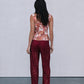 Woman wearing a floral top and red pants against a plain background