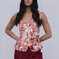 Woman wearing a floral top and burgundy pants against a plain background