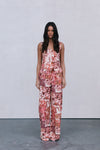 Woman wearing a floral jumpsuit pants and top on a plain background