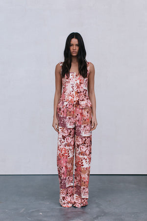 Woman wearing a floral jumpsuit pants and top on a plain background
