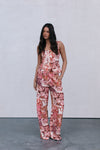 Woman wearing a floral jumpsuit pants and top against a plain background