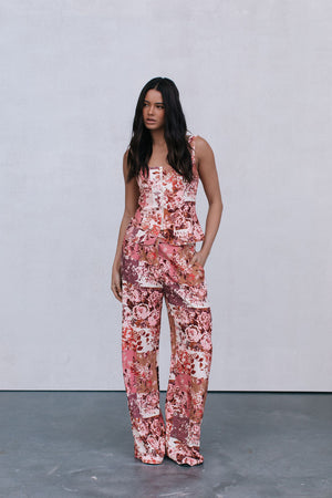 Woman wearing a floral jumpsuit pants and top against a plain background