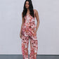 Woman wearing a floral jumpsuit against a plain background