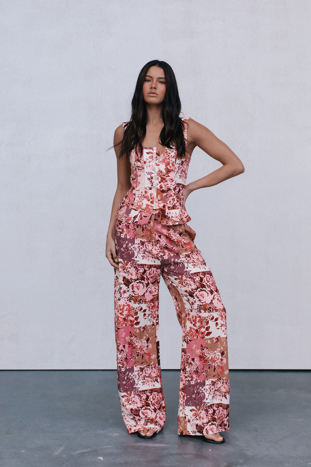Woman wearing a floral jumpsuit against a plain background