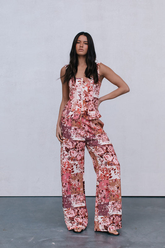 Woman wearing a floral jumpsuit against a plain background