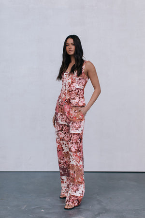 Woman wearing a floral jumpsuit against a plain background