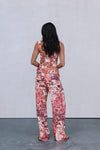 Person wearing a floral jumpsuit standing against a plain background