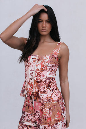 Woman wearing a floral top and pants against a plain background