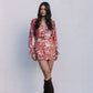 Woman wearing a floral dress and brown knee-high boots against a plain background