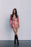 Woman wearing a floral dress and brown knee-high boots against a plain background