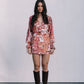 Woman wearing a floral dress and brown boots against a white background