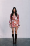 Woman wearing a floral dress and brown boots against a white background