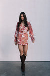 Woman wearing a floral dress and brown boots against a white background