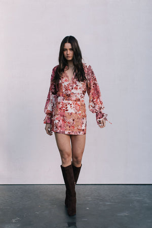 Woman wearing a floral dress and brown boots against a white background