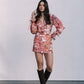 Woman wearing a floral dress and brown boots against a plain background