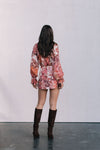 Person wearing a floral dress and brown knee-high boots against a plain background