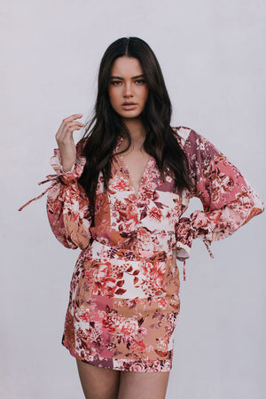 Woman wearing a floral blouse and mini skirt on a plain background