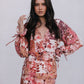 Woman wearing a floral dress with long sleeves on a plain background