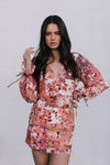 Woman wearing a floral dress with long sleeves on a plain background
