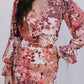 Woman wearing a floral dress with long sleeves on a plain background