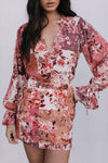 Woman wearing a floral dress with long sleeves on a plain background