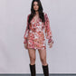 Woman wearing a floral dress and knee-high boots against a plain background