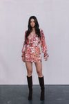 Woman wearing a floral dress and knee-high boots against a plain background