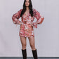 Woman wearing a floral dress with puffed sleeves and brown knee-high boots against a plain background