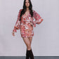 Woman wearing a floral dress with long sleeves and knee-high boots on a plain background