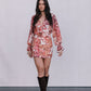Woman wearing a floral dress with long sleeves against a plain background
