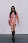 Woman wearing a floral dress with long sleeves against a plain background
