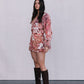 Woman wearing a floral dress and brown knee-high boots against a plain background