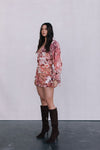 Woman wearing a floral dress and brown knee-high boots against a plain background