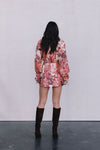 Person wearing a floral dress and knee-high boots against a plain background