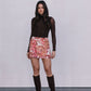 Woman wearing a brown top, floral skirt, and brown knee-high boots against a white background