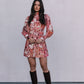 Woman wearing a floral dress and knee-high boots against a plain background
