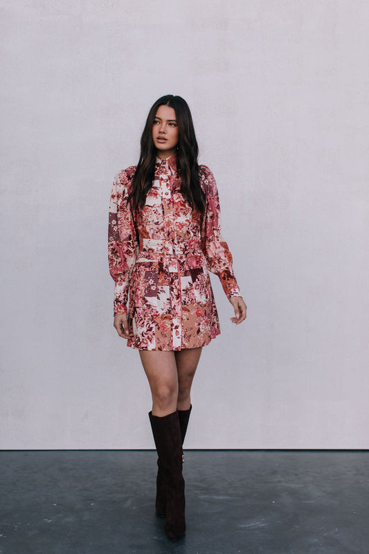 Woman wearing a floral dress and brown boots against a plain background
