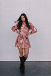 Woman wearing a floral dress and brown boots against a plain background