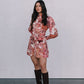 Woman wearing a floral dress and knee-high boots against a plain background