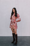 Woman wearing a floral dress and knee-high boots against a plain background