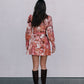 Person wearing a floral dress with long sleeves and knee-high boots on a plain background