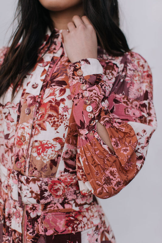 Person wearing a floral dress with long sleeves and a white background