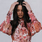 Woman wearing a floral patterned outfit against a plain background